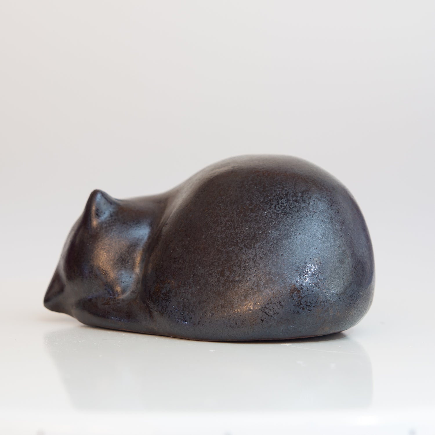 Kleine, zusammengerollte Keramik-Katze in schwarz