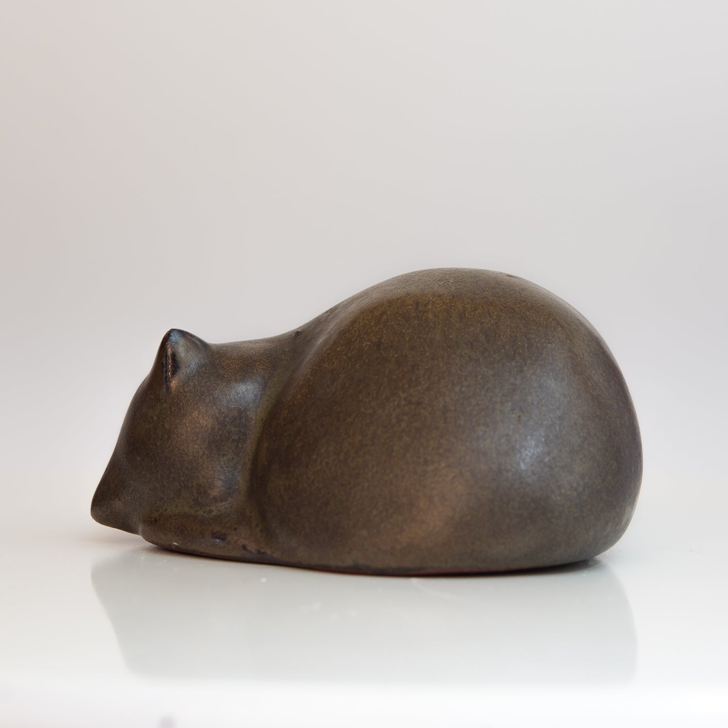 Kleine, zusammengerollte Keramik-Katze in braun