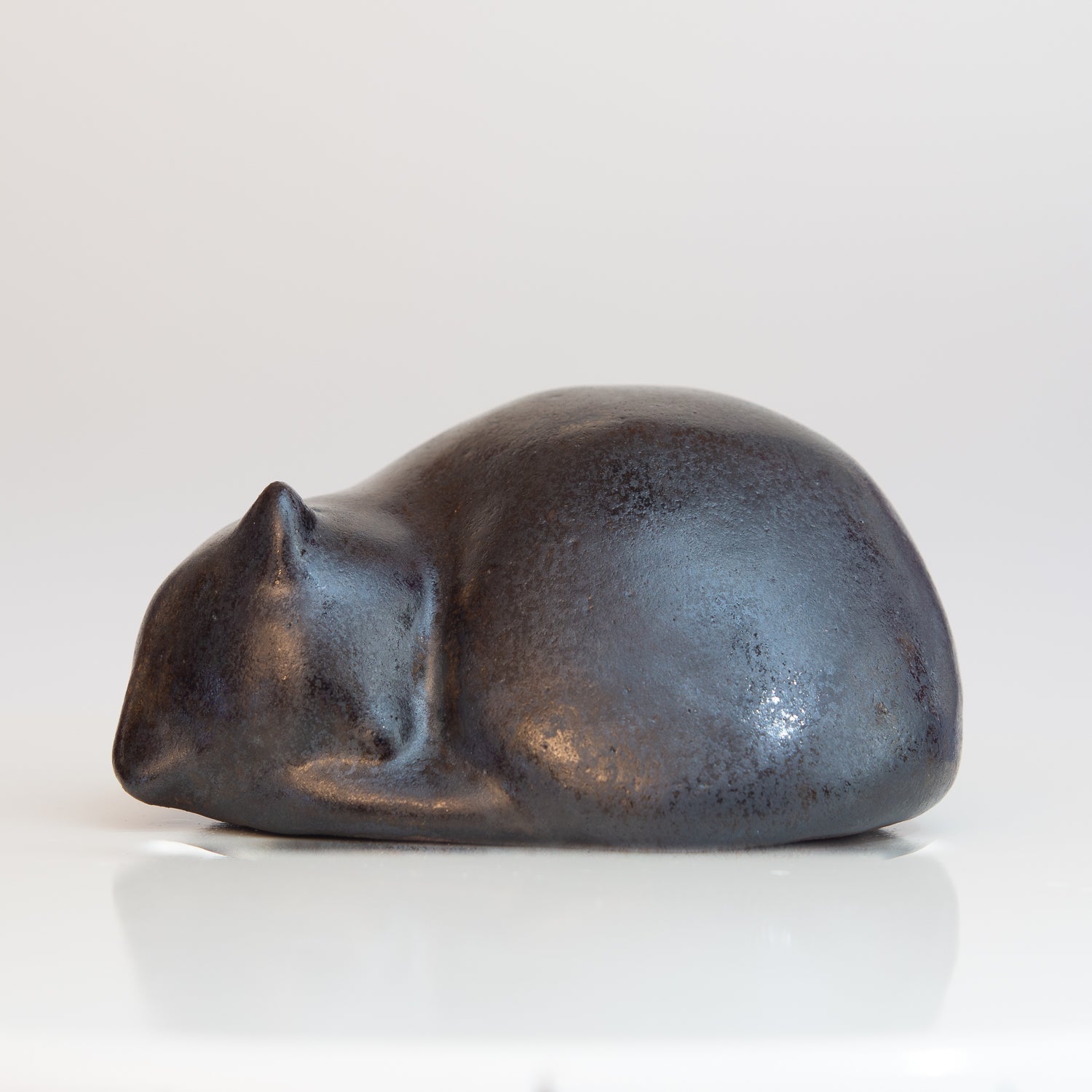 Kleine, zusammengerollte Keramik-Katze in schwarz